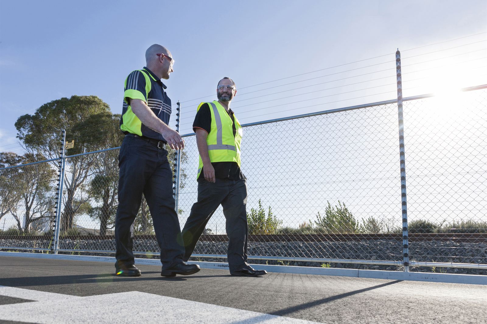Technicians walking a Gallagher monitored pulse fence on an industrial perimeter